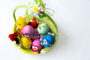 Easter eggs in pastel colors with a decor in the form of birds lie in a beautiful green basket, copy space