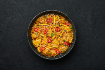 Chicken Handi in black bowl on dark slate table top. Murgh Chicken is indian cuisine curry masala dish. Asian food and meal. Top view