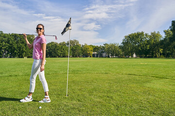 Joyous golf player standing near the flagstick