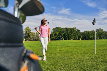 Slim lady carrying an iron golf club
