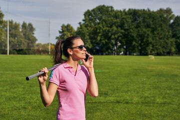 Attractive golf player using her gadget outside