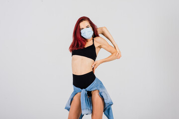 Obraz premium Female dancer in the styles of strip-plastic and pole dance with face mask on light background.
