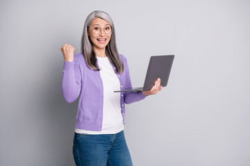 Fortune is on my side today. Photo portrait of funny elder secretary smiling cheerfuly laughing feeling happy lucky holding laptop writing emails isolated on grey color background