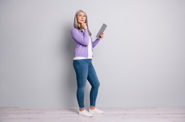 Full length body size photo of concentrated elder businesswoman working with laptop looking at side touching her face wearing eyeglasses casual clothes isolated on grey color background