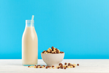Breakfast cereal balls and milk in glass against blue background