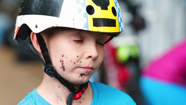 Emotions of a teenager's experience at sports competitions. He wipes dirt off his face with his hand. Sports activities in the forest.