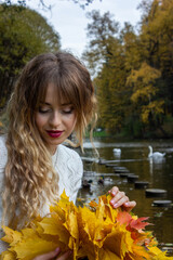 Beautiful girl in a wreath of autumn leaves.