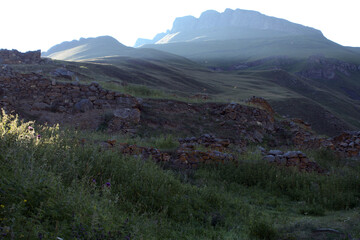 Naklejka premium Ruins of an old house in the misty hills. The walls of the old kosh in the mountains. Ruins of the old settlement Shyky. The Balkan poet Kazim Mechiev lived in this village. Caucasus, Russia.
