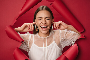 Young caucasian brunette happy woman plugging her ears with fingers