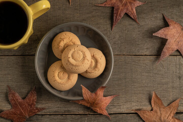 cup of coffee and cookies on a wooden table decorated dried autumn leaves