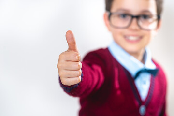 Schoolboy in a sweater shows a thumb up to the camera. Conceptual. Copy space.