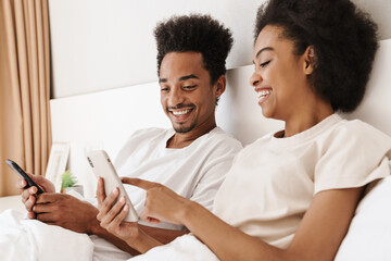 Fototapeta premium Dark skinned man and his wife use mobile phones