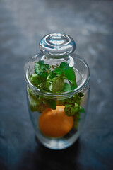 Glass vase stands on the table, and there are tangerines in it.
