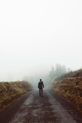 Man's silhouette walking in foggy mountains