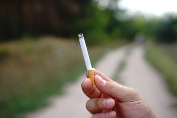 Man hand holding cigarette. Cigarette in hand. Unhealthy lifestyle concept.