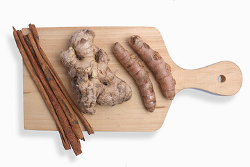 Fresh turmeric and ginger with cinnamon sticks on cutting board