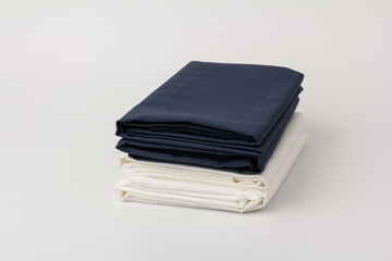 Stack of clean white and blue bed sheets on white  background, closeup.