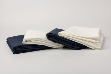 Stack of clean white and blue bed sheets on white  background, closeup.