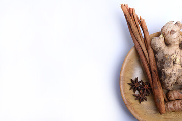 Fresh turmeric and ginger with cinnamon sticks on wooden plate