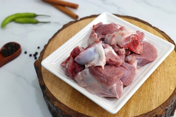 Fresh raw goat meat or mutton or lamb pieces. Preparation for Indian mutton curry. Spice at the background such as cinnamon sticks, red chili powder, black pepper & coriander. Copy space.