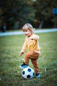 Little boy playing football alone on the grass.