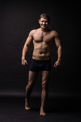 Fototapeta premium Handsome man in underwear on the black background. Muscular and athletic. Underwear man portrait. Male underwear model in studio 