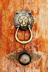 Heurtoir en métal avec une tête de lion sur une vieille porte en bois