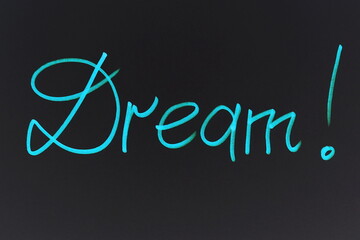 The word Dream written by hand on a black background