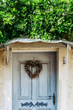 Porte d'entrée d'un maison en bois avec une couronne décorative en forme de coeur