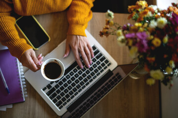 Shot of an unrecognizable woman working from home. Woman holding a cup off coffee