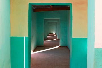Arched corridor without doors in pastel colors where rows of light slip through 