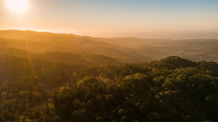 Sunset or sunrise over wild forest mountains. Aerial photo of the mountain tops with sunlight