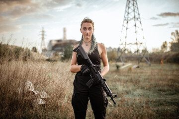 Fototapeta premium Sexy woman posing with a rifle outdoors on the background of the Chernobyl sarcophagus