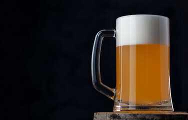 Glass mug of wheat foam beer on a dark background