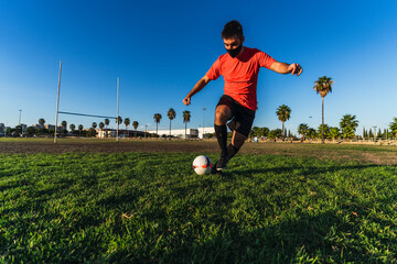 Chico joven con mascarilla por el covid 19 preparandose y jugando al futbol