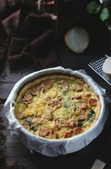 Quiche Lorraine, French tart made from pastry crust,milk, cheese, sausage and vegetables. Wooden textured background.