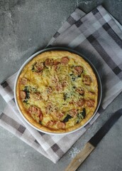 Quiche Lorraine, French tart made from pastry crust,milk, cheese, sausage and vegetables. Wooden textured background.