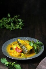 Pindang Ikan Bandeng, Indonesian fish soup on ceramic plate. Dark wooden background.