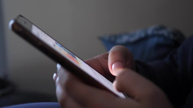 Teenager girl fingers typing on her smartphone at home texting a message.