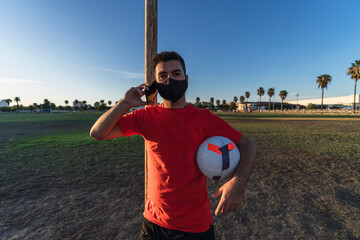 Chico joven con mascarilla por el covid 19 preparandose y jugando al futbol © MiguelAngelJunquera