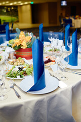 Table setting with white plates , blue serviettes and cutlery on table, copy space. Place setting at Christmas party. Table served for New year banquet in restaurant