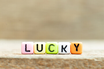 Colorful bead with black letter in word lucky on wood background