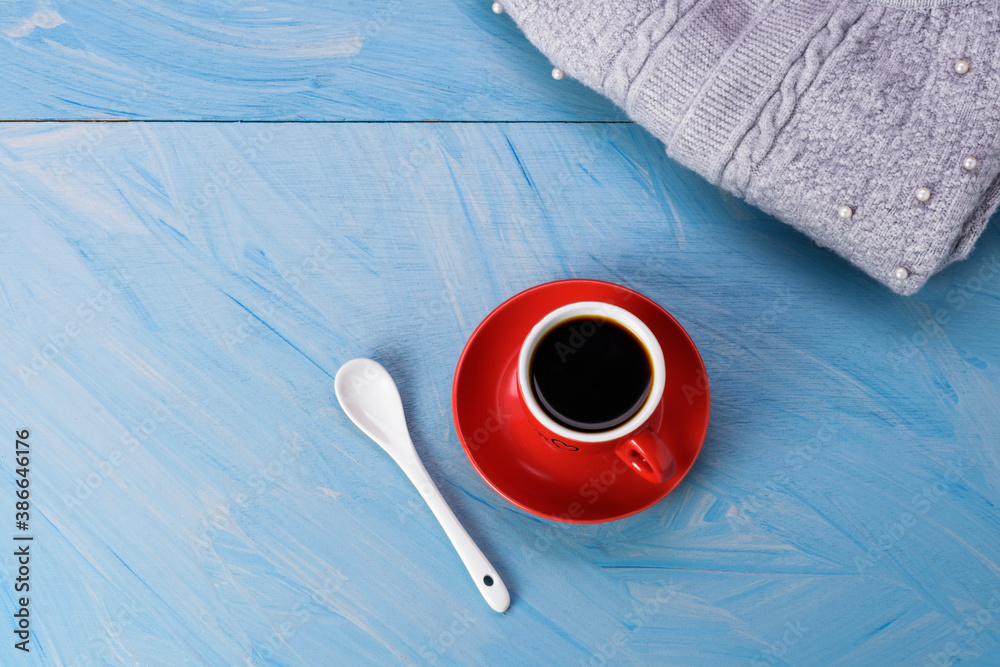 Wall mural Gray knit sweater With coffee cup and spoon placed on a blue wooden table - top view