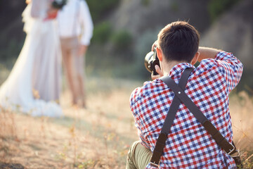 wedding professional photographer takes pictures of the bride and groom in nature on the sunset, man photographer in action