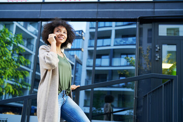 Woman standing on city steps and talking on the phone