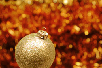 Golden Christmas ball on blurred sparkling background. Christmas background. Festive holiday concept.