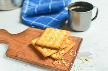 Cracker and coffee on the wooden chopping board on the table