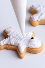 Close up of decorating cute Halloween cookies with frosting in icing bag.