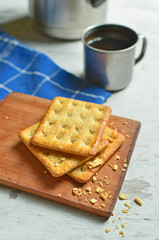 Cracker and coffee on the wooden chopping board on the table