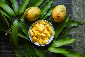 Sliced green mango with chili powder , salt street food snack Kerala India. Organic Fresh green mango on mango leaf background. Indian Traditional Raw Mango Pickle. Bengali seasonal fruit unripe mango